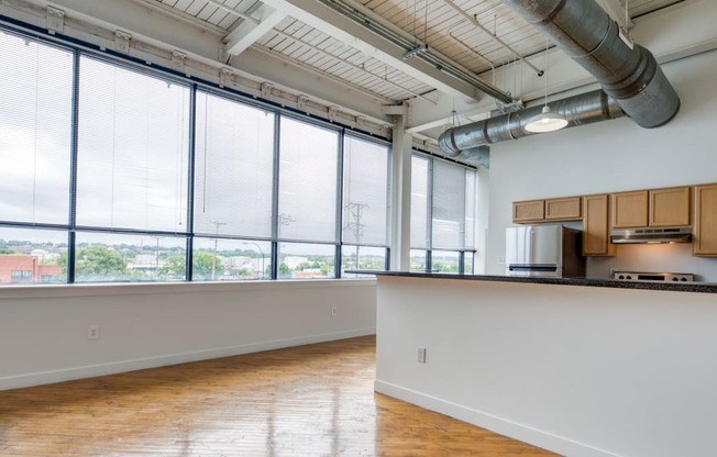 an empty room with a large window and a kitchen