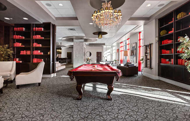 A room with a pool table and a chandelier.