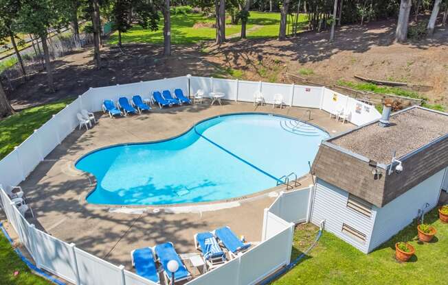 a resort style swimming pool with blue chairs and a building next to it