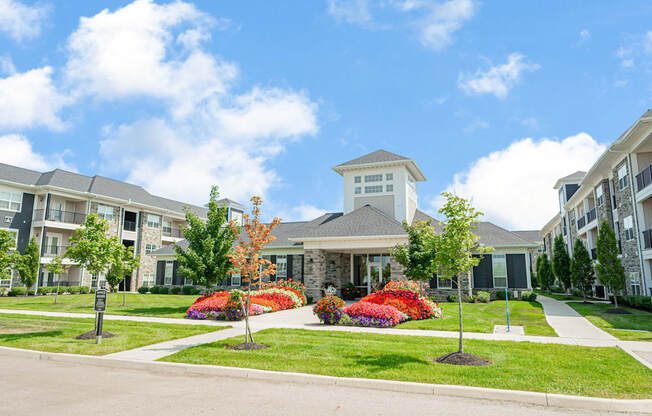 an exterior view of an apartment building with a lawn and flowers