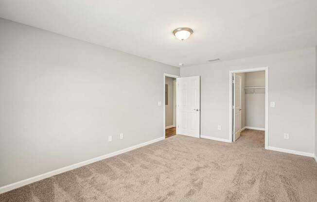 A room with carpeted floor and two open doors.