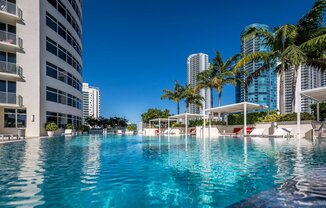 a swimming pool with palm trees in front of a tall building at Regatta at New River, Florida