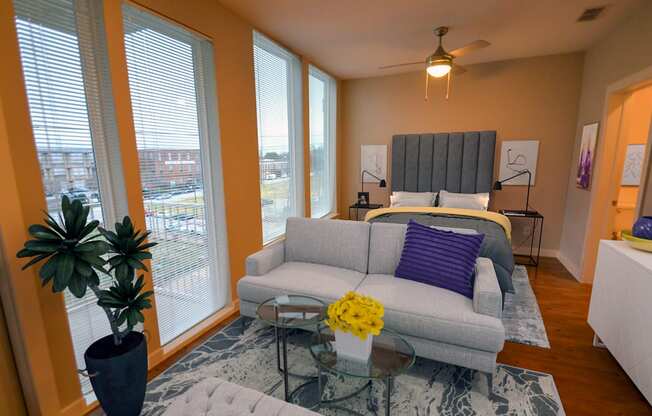 a living room with a couch and a bed in a room with large windows at Link Apartments® Canvas, Atlanta, GA, 30312