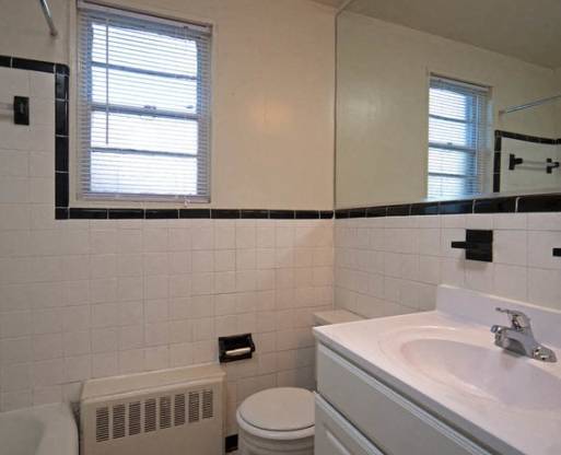 A bathroom with a white toilet, sink, and a window at battery lane apartments in bethesda maryland.