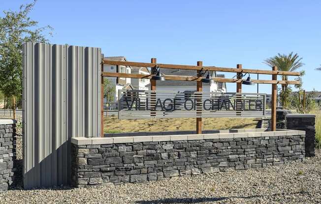 a stone retaining wall with a metal fence and a sign for the entrance to the