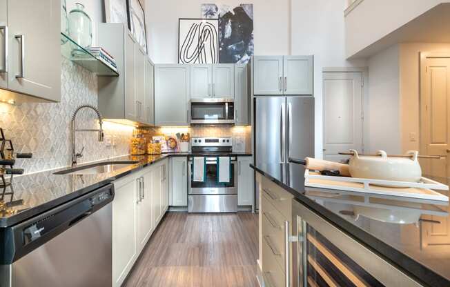 Kitchen with black quartz countertops and stainless steel appliances facing the sink and wine cooler.