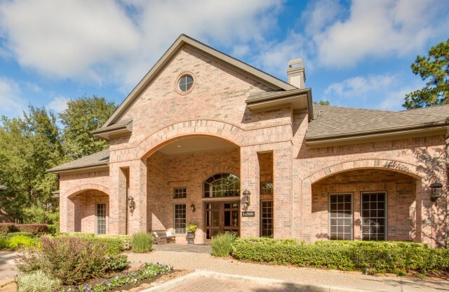 View of Resident Clubhouse with Entrance, Landscaping, and Bench at Raveneaux Apartments