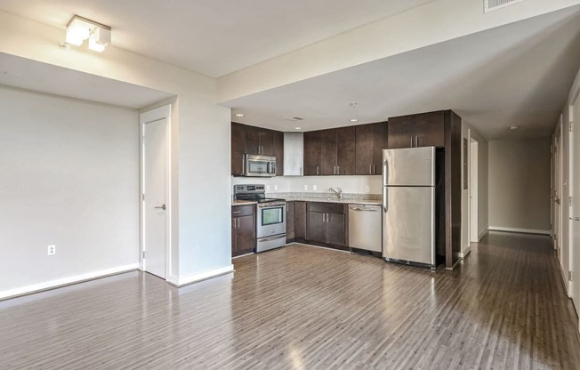 an empty kitchen with stainless steel appliances and wooden floors