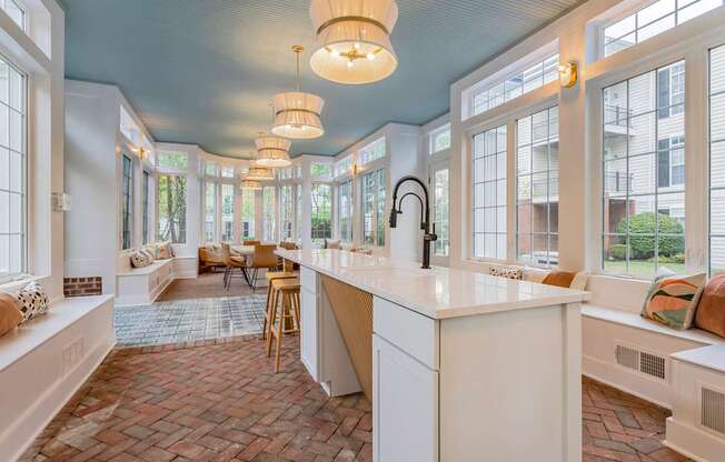 A kitchen with a white counter and wooden chairs.