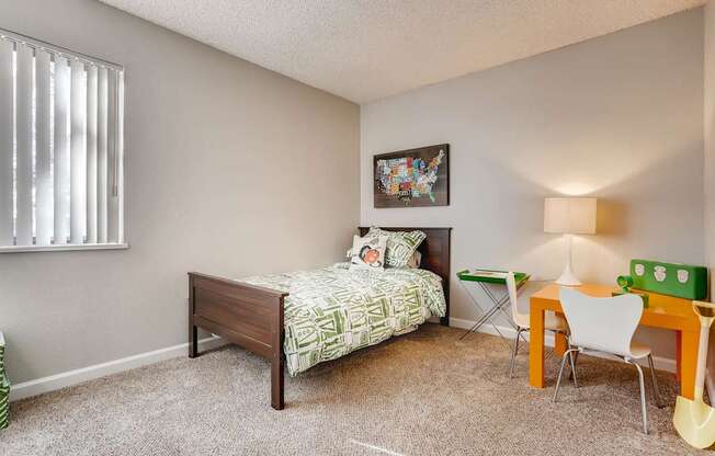A bedroom with a bed, chair, and a painting on the wall.