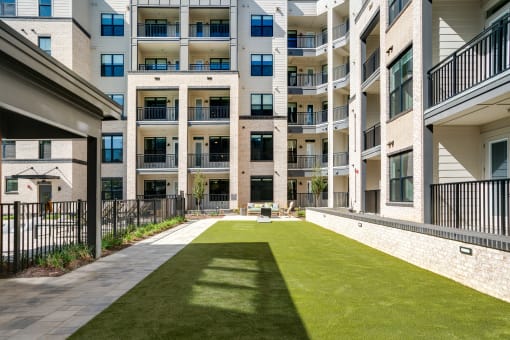 an apartment courtyard with a grass lawn in front of an apartment building