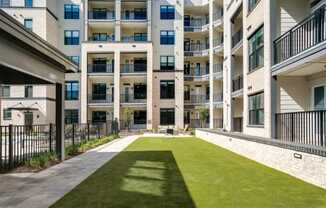 an apartment courtyard with a grass lawn in front of an apartment building