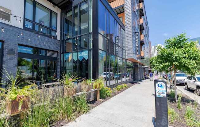 A modern building with a glass facade and a parking sign on the sidewalk.