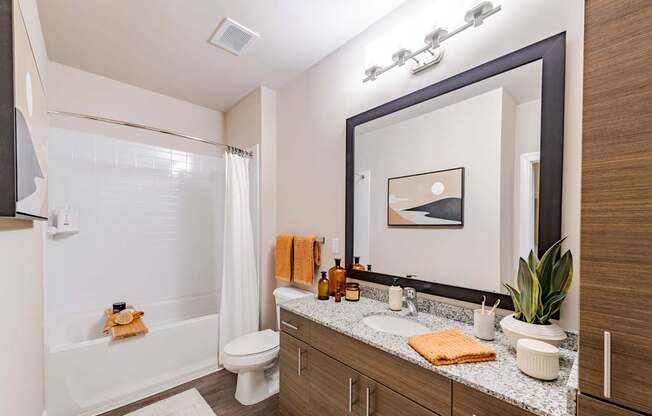 A bathroom with a white tub, sink, and mirror.