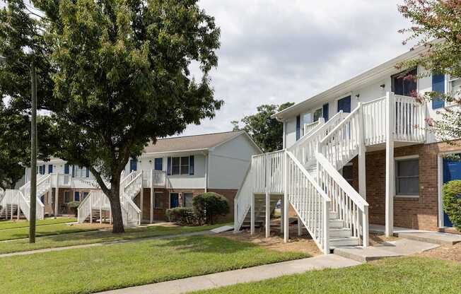 A white two-story house with a balcony and stairs leading to the second floor.