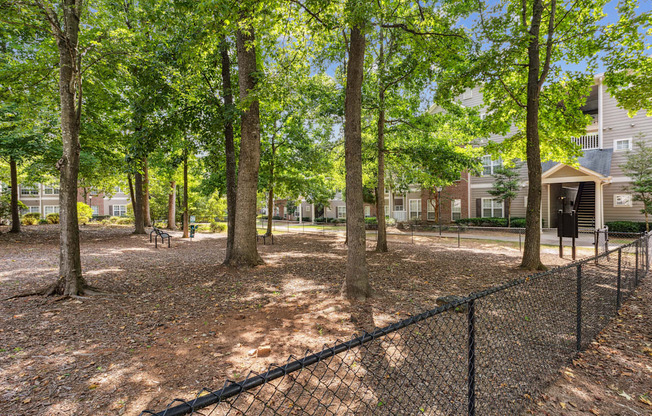 a fenced in dog park with trees and houses