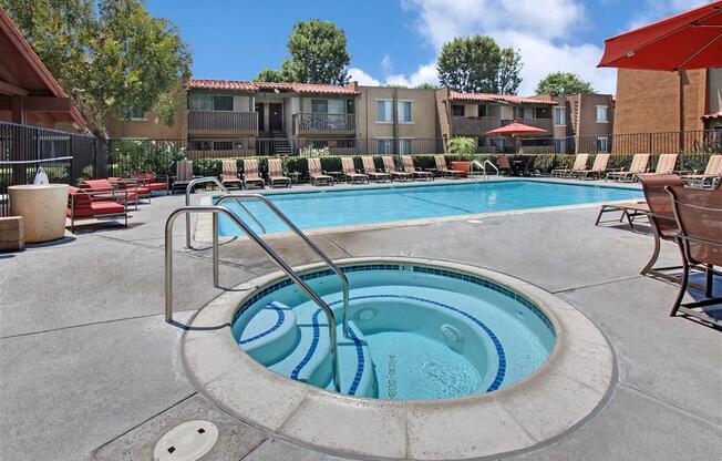 Community pool and hot tube with deck chairs and umbrellas on beautiful day