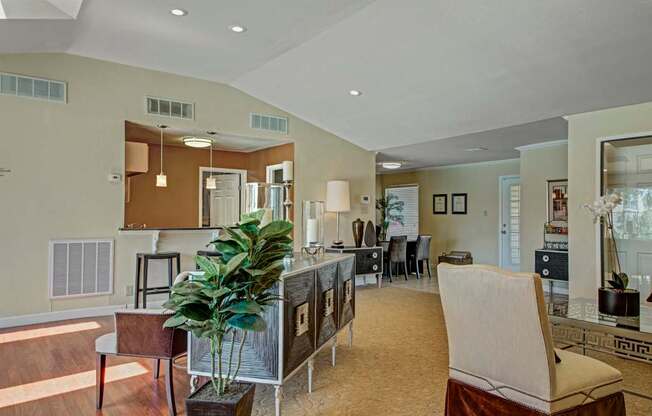 A spacious resident lounge here at Cypress Pointe with an open-concept layout, warm wood-style flooring, and modern décor creating a comfortable, welcoming feel. A breakfast bar, soft lighting, and multiple seating areas make the space ideal for socializing or relaxing.