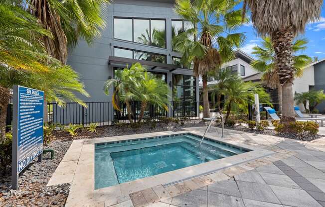 a swimming pool in front of a building with palm trees