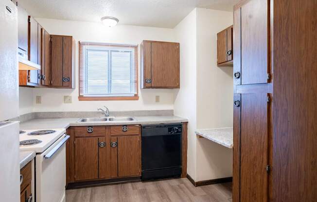 A kitchen with wooden cabinets and a black dishwasher. West Fargo, ND Parkwest Gardens