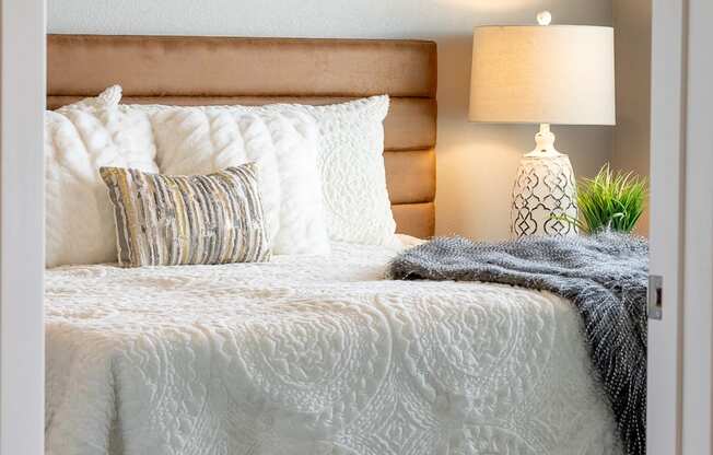 a bedroom with a bed and pillows and a lamp