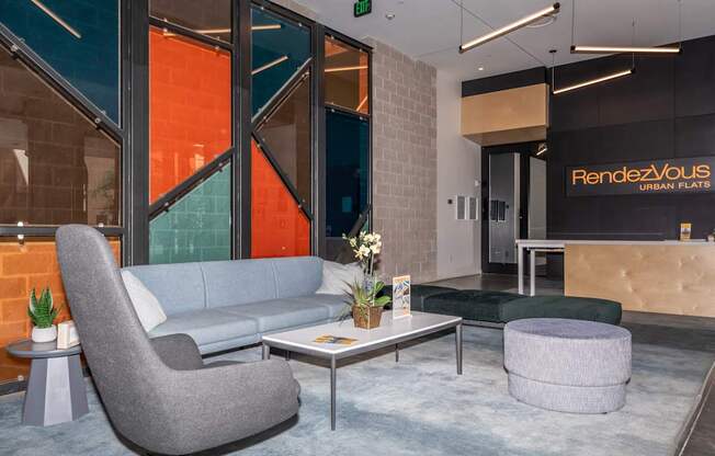 A grey chair is in front of a glass wall with a sign that says "Rendezvous Urban Flats".