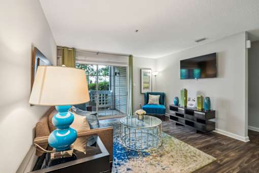 A blue lamp sits on a table in a room with a glass table and a sofa.