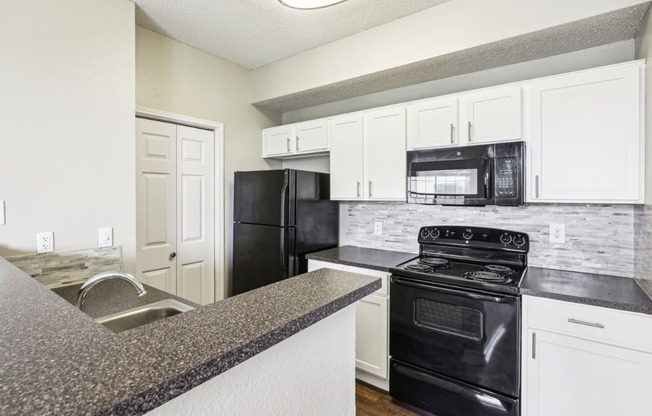 A2 floor plan updated kitchen with black appliances and white cabinets at Jefferson Creek Apartments in Irving, TX.