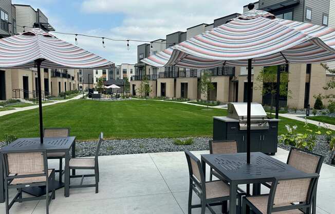 a patio with tables and umbrellas and a lawn in front of apartments at Meridian at CityPlace in Woodbury, MN 55125