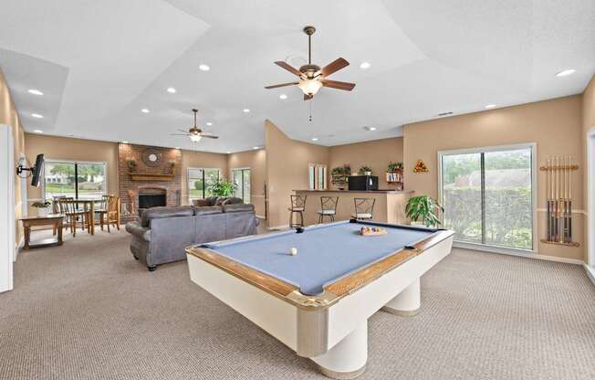 A pool table is in the middle of a room with a ceiling fan.
