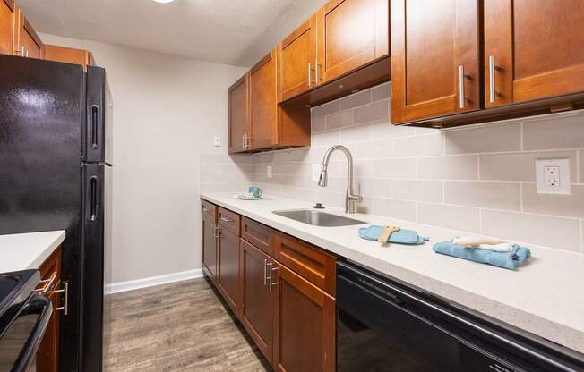A kitchen with a black fridge and wooden cabinets.