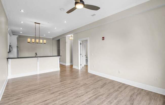 an empty living room with a ceiling fan and a kitchen at The Knights @ 506 Delaware Apartments, New York, 14202