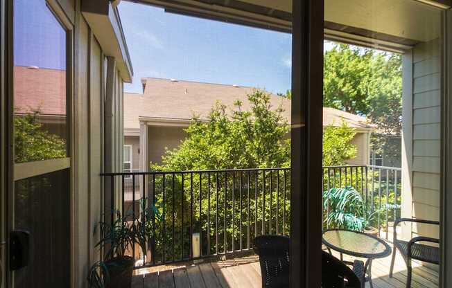 A balcony with a table and chairs is visible through the patio sliding doors in a 1 bedroom, 1 bath 554 sq ft apartment home at The Biltmore Apartments located in the Vickery Midtown neighborhood of Dallas, TX.