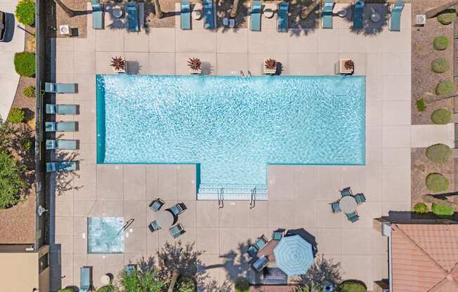 A large rectangular pool surrounded by chairs and plants.