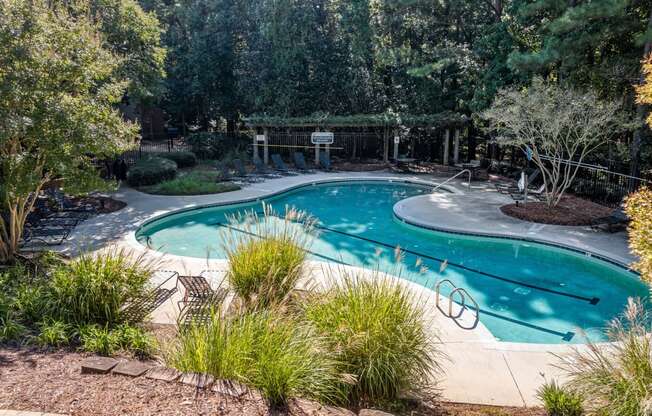 a swimming pool is surrounded by trees and plants at View at Lake Lynn, Raleigh, NC