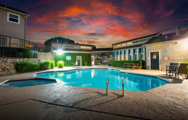 A swimming pool at night with lights on.