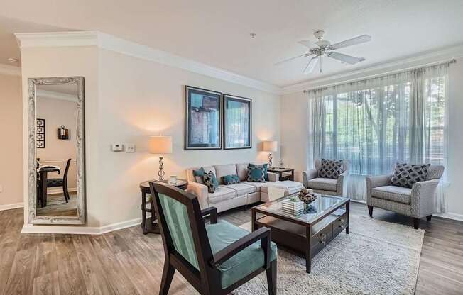 A living room with a chair, a sofa, a table, and a mirror.