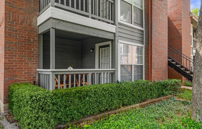 A balcony with a railing and a hedge in front of a brick building.