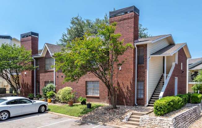 A house with a red brick exterior and a white car parked in front.
