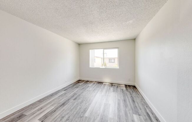 a bedroom with hardwood floors and white walls