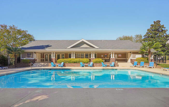 A large swimming pool in front of a building with a blue sky in the background.
