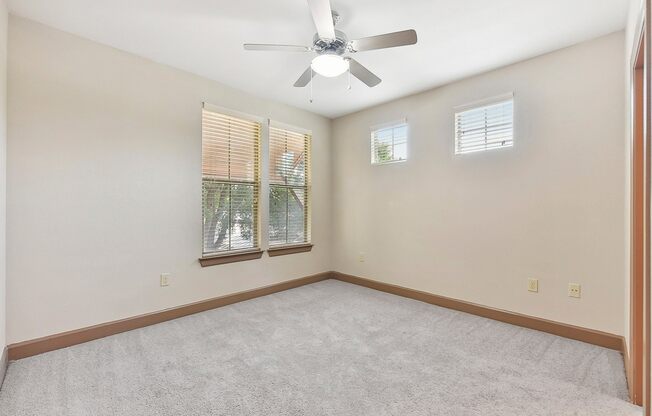 an empty room with a ceiling fan and two windows at Lakeline East Apartments, Texas, 78613