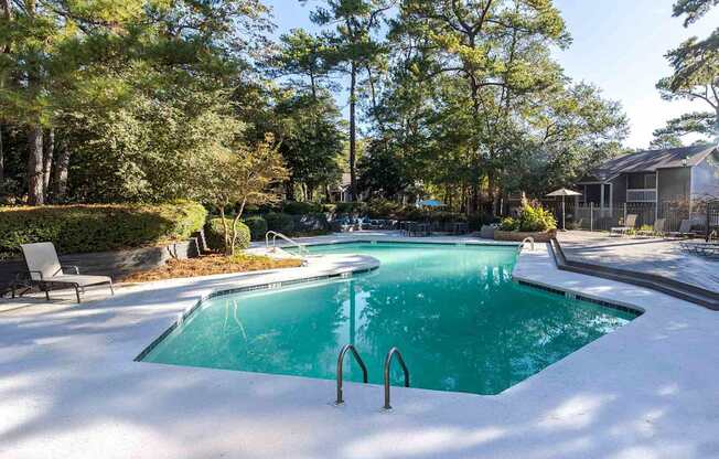 A swimming pool surrounded by trees and a house in the background.