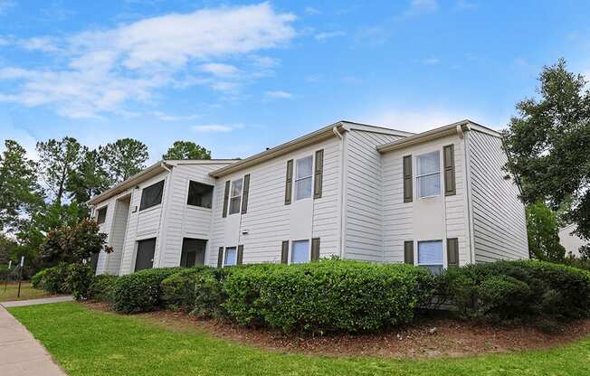 an apartment building with white siding and a sidewalk