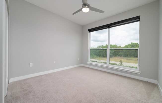 an empty room with a large window and a ceiling fan