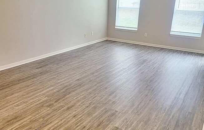 an empty living room with wood floors and a ceiling fan