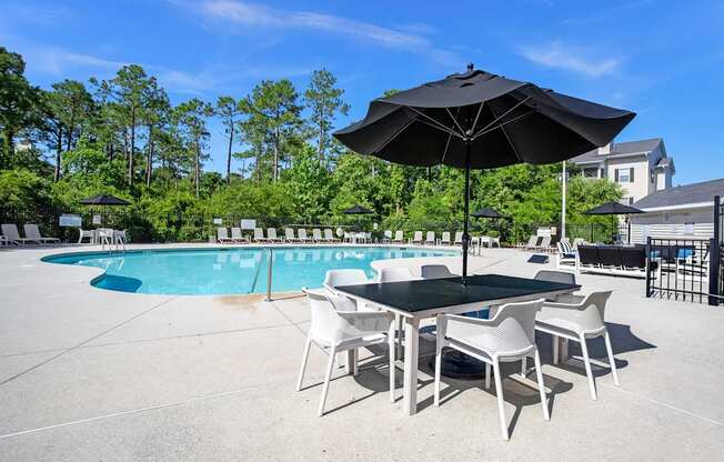 A black umbrella shades a table with four chairs.