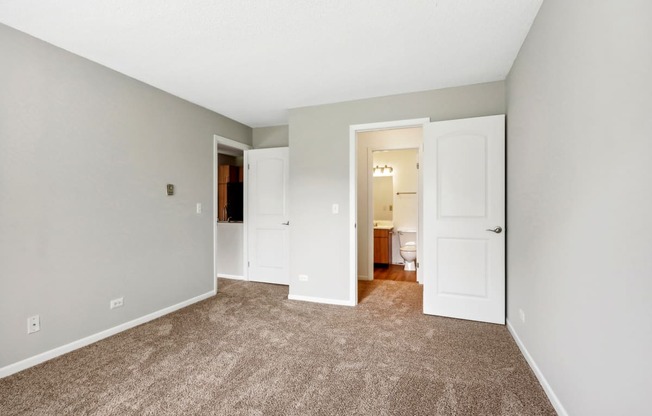 an empty living room with carpet and a door to a bathroom