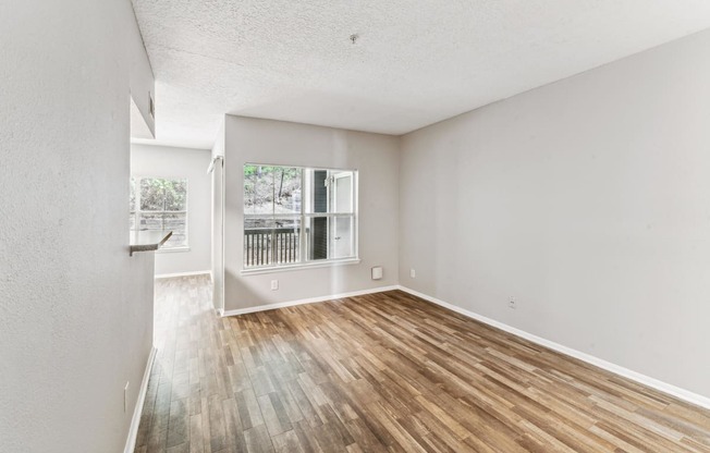 an empty living room with wood flooring and a window
