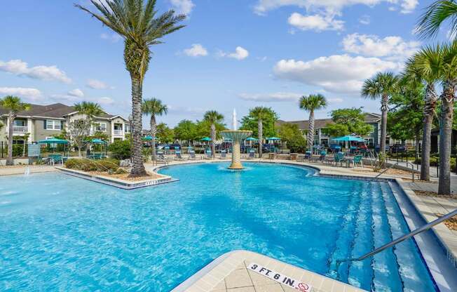 A large pool with a slide and palm trees around it.